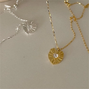 Close-up of gold and silver heart necklaces featuring textured metal and clear zircon