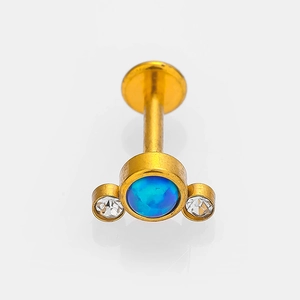 Macro detail of golden labret stud with blue opal and clear cubic zirconia stones