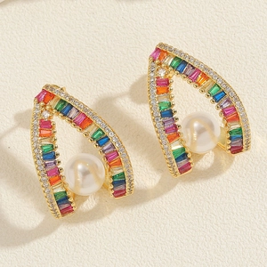 Macro view of gold arch earrings with rainbow zircons and a central white pearl
