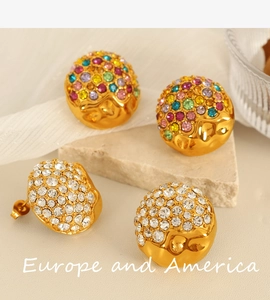 Macro view of gold heart stud earrings with colorful rhinestones and hammered metal texture