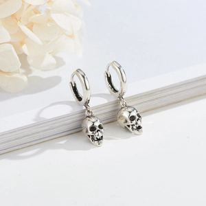Retro silver punk skull earrings with vintage finish on high quality white book background