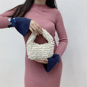 Detail showing the white textured plush chenille handbag held by a model in a pink dress