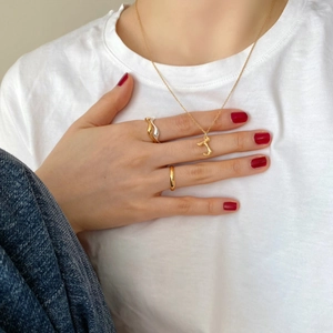 Detail of 925 silver gold-plated cursive letter necklace and interlocking rings on model
