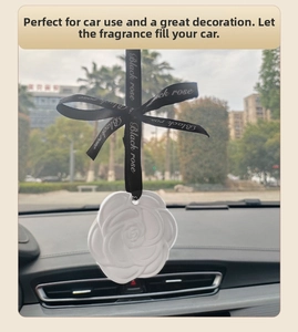 Detailed close-up of a white camellia plaster diffuser hanging in a car interior