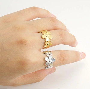 Detalle de anillos de flores de acero inoxidable en oro y plata usados en la mano