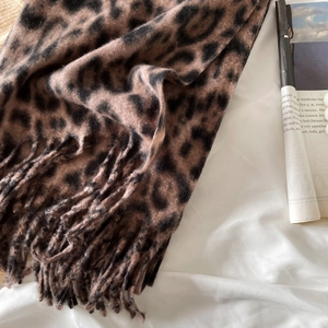 Detail of leopard print scarf with fringes on soft fabric next to a vintage newspaper