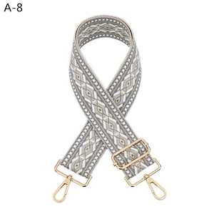 Detail of adjustable gray diamond pattern woven shoulder strap with gold metal lobster clasps