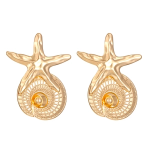 Macro detail of golden starfish and spiral shell earrings with textured metallic finish