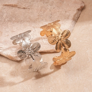 Detailed close-up showing textured metallic flower petals on gold and silver cuff bracelets