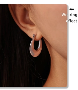 Close-up of model wearing a minimalist silver U-shaped earring with polished metal finish