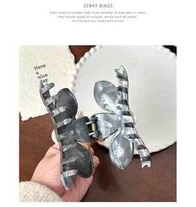 Detail of a large butterfly hair claw clip with grey marble pattern and metal spring
