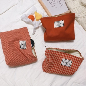 Three-piece set of orange canvas makeup bags with houndstooth pattern and metal zippers