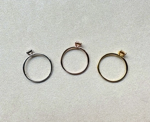 Three Asscher-cut moissanite rings in silver, gold, and rose gold plating on a textured base