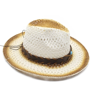 Dettaglio cappello da cowboy in paglia traforata con tesa sfumata e cinturino decorato