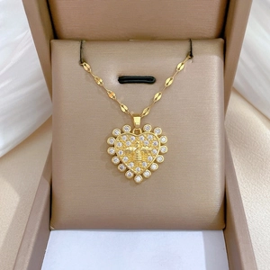 Macro detail of gold heart pendant necklace with zircon border and center bee charm