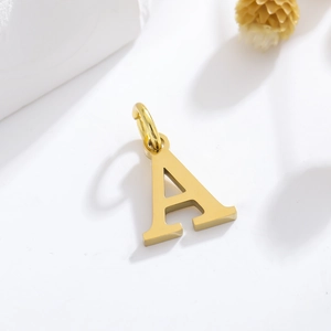 Gold letter A alphabet pendant necklace charm on white background with dried flowers