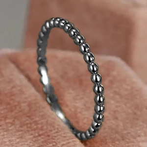 Macro di un anello minimalista a sfere in argento scuro su supporto in velluto rosa