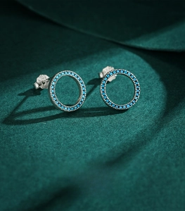 Macro view of S925 sterling silver hollow turquoise stud earrings on green fabric