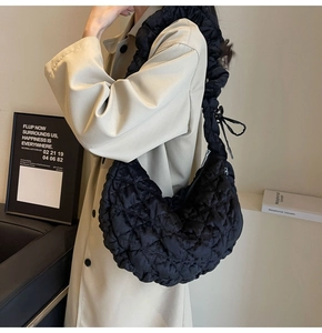 Minimalist black quilted bubble shoulder bag shown styled on a model in soft studio lighting