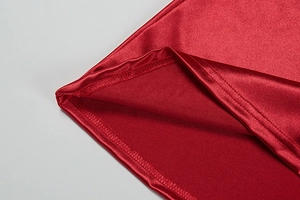 Detail shot of the red satin dress hem showing fine stitching and lustrous fabric texture