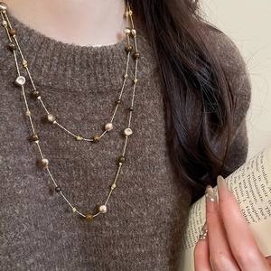 Close-up of a double-layered tiger eye beaded necklace on a brown knit sweater
