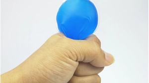 Close-up of hand squeezing flexible blue PVC cooling gel eye mask pad to show its soft texture