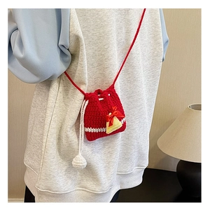 Detailed view of a handmade red crochet Christmas crossbody bag with a bell charm