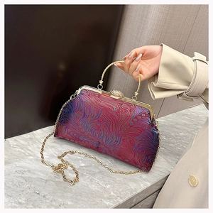 Detail of red Chinese style handbag with blue peacock feather patterns and metal handle