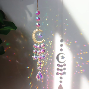 Detail of crystal suncatcher with gold moon and star reflecting rainbow spots on wall