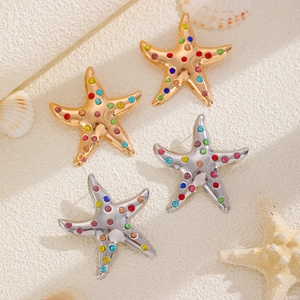 Summer beach style starfish earrings with colorful rhinestones on a sand-like background