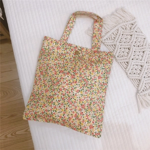 Détail du sac cabas en toile fleurie avec bouton pression sur support matelassé