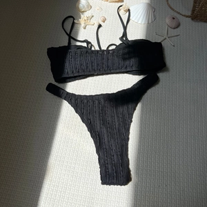 Detail der schwarzen gerippten Textur des Bikinis mit maritimer Dekoration am Strand