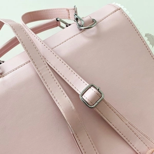 Detail of pink leather backpack featuring adjustable silver buckles and white wavy edges