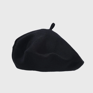 Close-up of a black knit beret showing its textured fabric and decorative top stalk detail