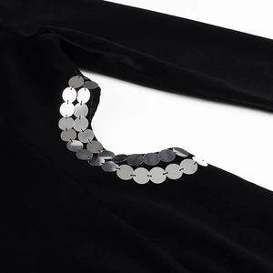 Détail de robe en velours noir avec paillettes argentées et découpe à l'épaule