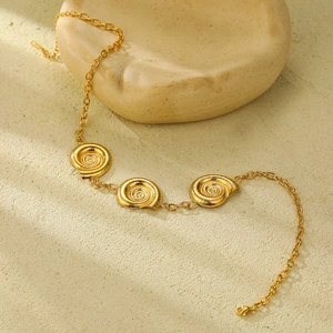 Detailed shot of 18k gold plated stainless steel bracelet with snail spiral charms