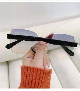 Macro detail of rimless sunglasses featuring blue-yellow gradient lenses and black temples