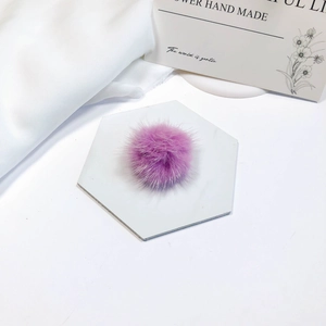 Close-up of a soft purple mink fur pompom on a decorative white hexagonal tile