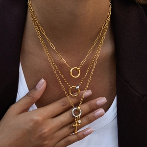 Close-up of gold and silver layered necklace with cross pendant on professional model