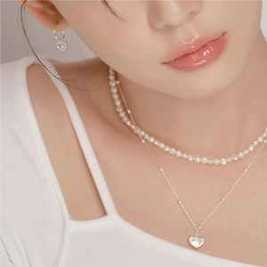 Detail of layered heart pendant necklaces and pearl chain with matching heart earrings