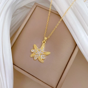 Elegant gold starfish pendant necklace with cubic zirconia on white silk backdrop