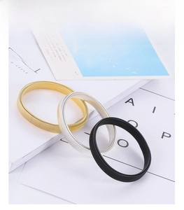 Detailed close-up of metal spring armbands in gold, silver, and black on a white background