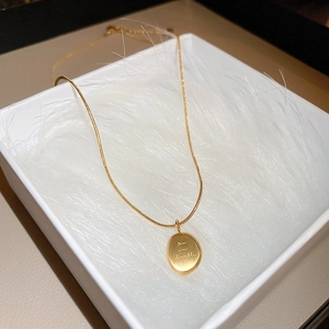 Détail du pendentif ovale doré avec texte gravé you are lovable dans son coffret cadeau