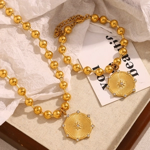 Dettaglio della collana e del braccialetto a catena a sfere placcati oro 18 carati con sole