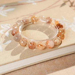 Macro shot of natural red rutilated quartz beaded bracelet on a decorative fabric book