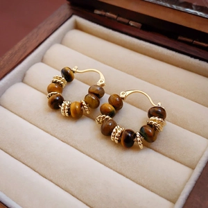 Detail of tiger eye bead hoop earrings with gold plating on a velvet jewelry box