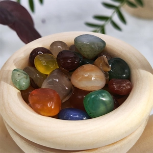Close-up of polished natural gemstones in a light wooden bowl for essential oil diffusion