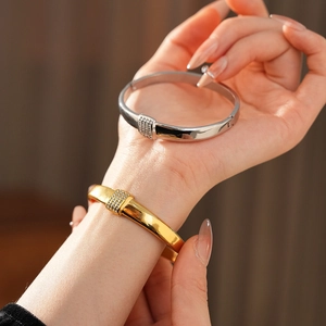 Détail de bracelets en acier titane doré et argenté sertis de strass portés au poignet