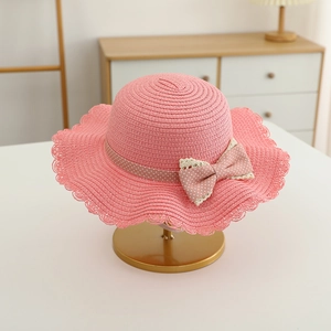 Detail of pink straw hat for girls featuring a polka dot ribbon and lace bow trim
