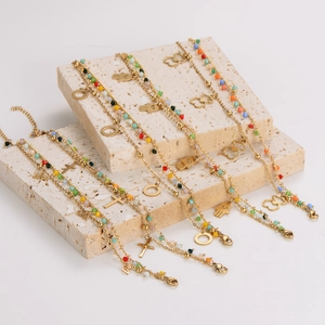 Bohemian gold layered bracelets with colorful beads, evil eye and cross charms on marble stand